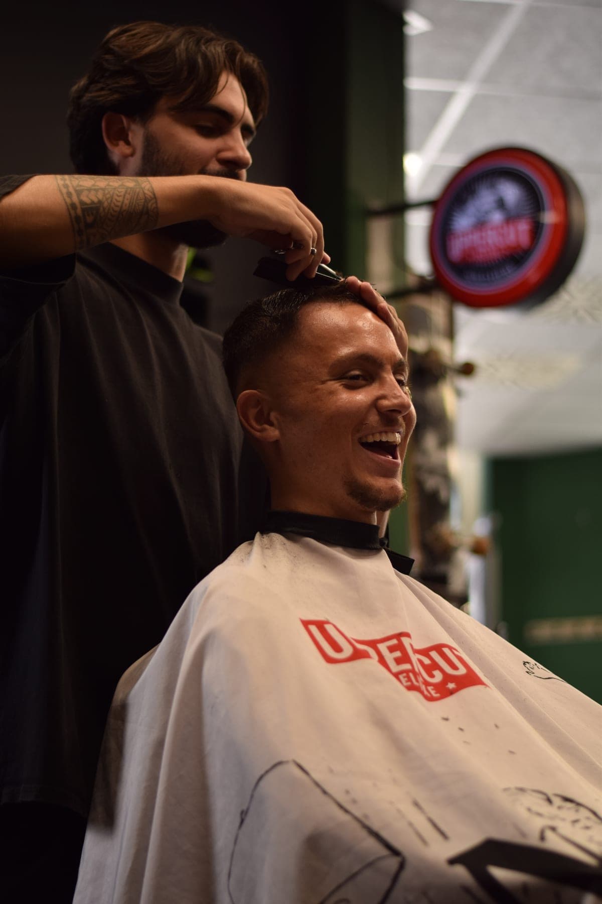 Barber cutting the hair of a smiling client at Porem Barbershop Amsterdam