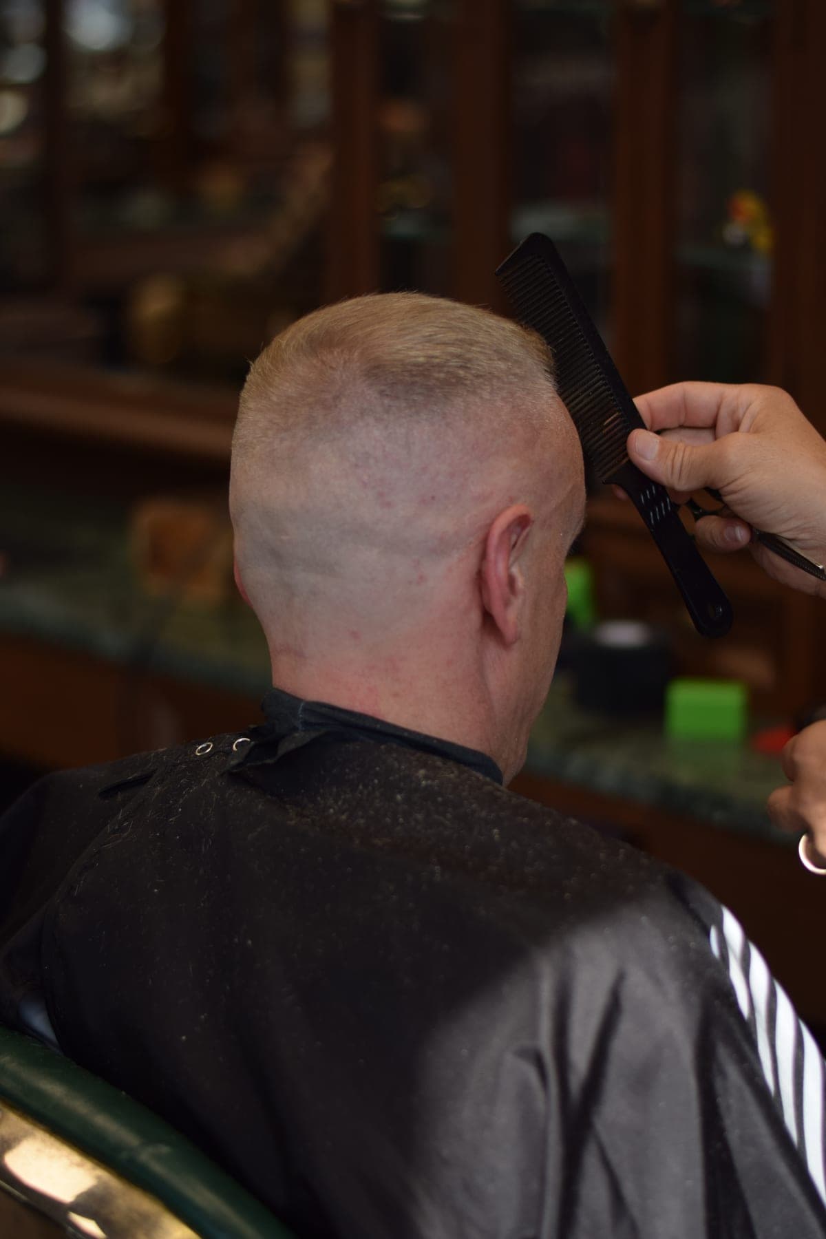 Barbier controleert een buzz cut met een kam bij Porem Barbershop Amsterdam