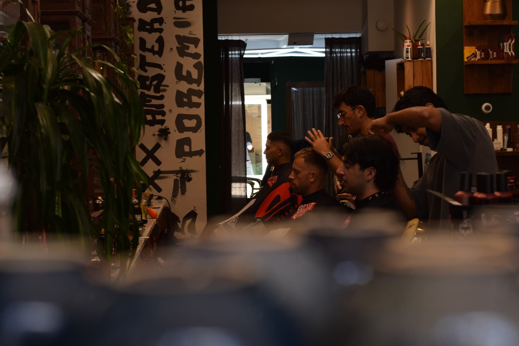 Barbers at work under the hand-painted POREM mural at Porem Barbershop Amsterdam