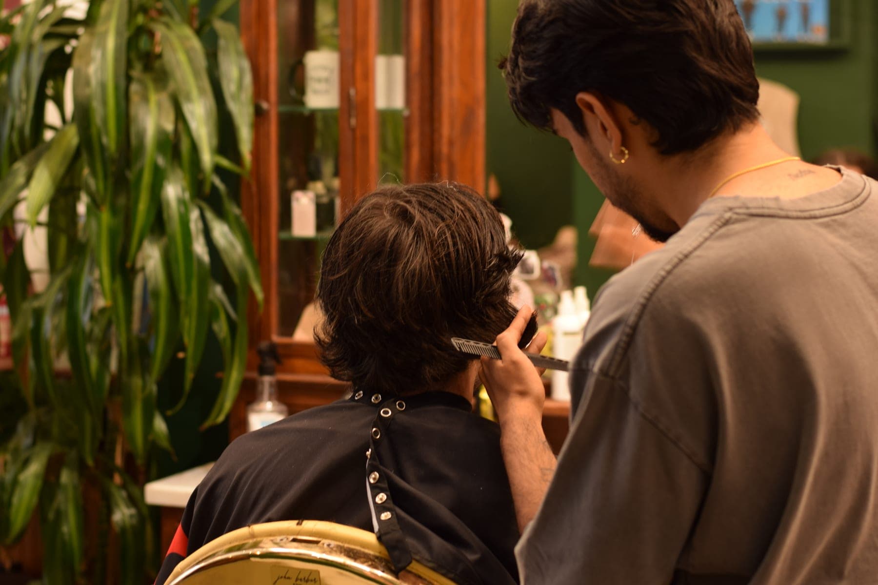 Barber trimming a client among the plants at Porem Barbershop Jordaan Amsterdam